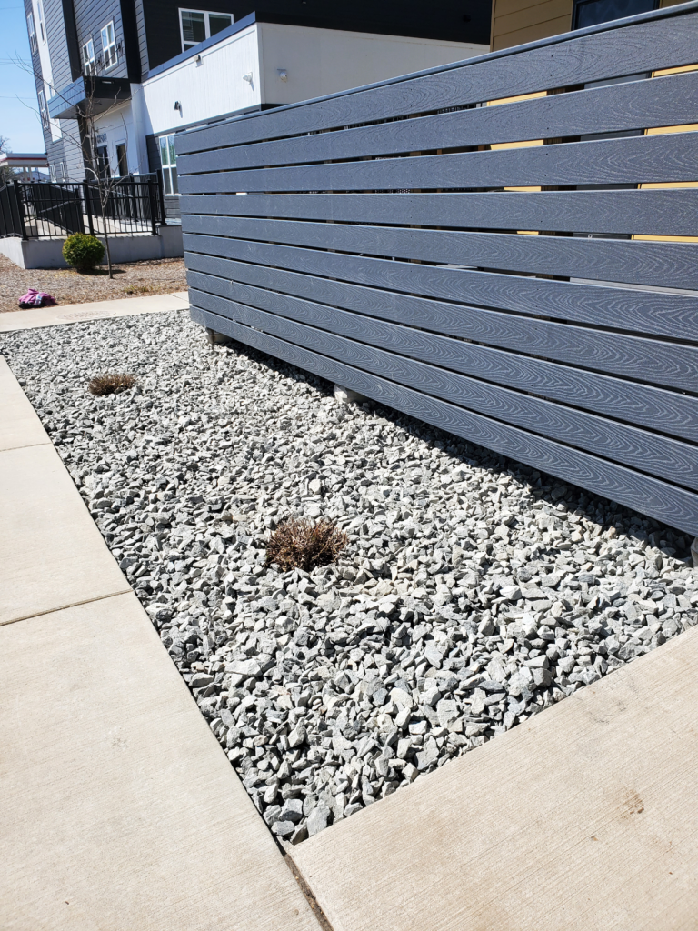 A clean landscaping bed featuring professionally installed decorative rock and neat edging around an Eau Claire home.